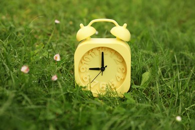 Photo of Yellow alarm clock on green grass outdoors