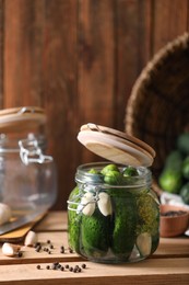 Glass jar with fresh cucumbers and other ingredients on wooden table. Canning vegetable
