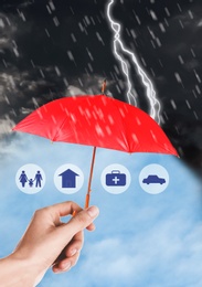 Insurance concept. Woman protecting illustrations with red umbrella from storm, closeup