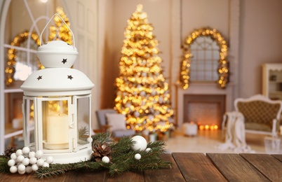 Composition with Christmas lantern on table in decorated room, space for text