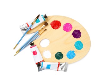 Wooden artist's palette with brushes and paints on white background, top view