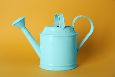 Photo of Turquoise metal watering can on yellow background