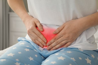 Woman suffering from abdominal pain at home, closeup