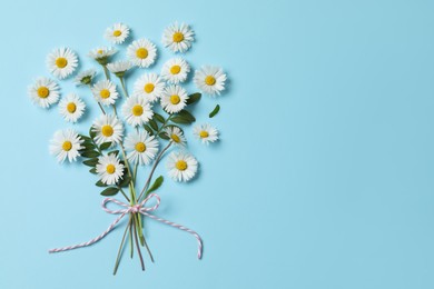 Flat lay composition with daisy flowers and leaves on light blue background. Space for text