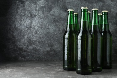 Photo of Bottles of beer on grey table. Space for text