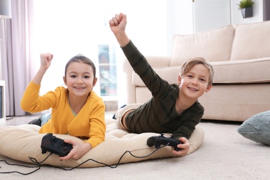 Cute children playing video games on floor at home