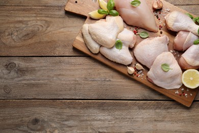 Board with fresh raw chicken wings and other products on wooden table, top view. Space for text
