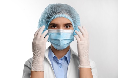 Doctor with medical gloves, mask and cap on white background