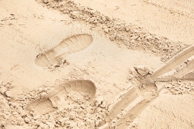 Sand with footprints, bird tracks and wheel trail