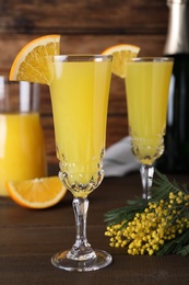 Glasses of Mimosa cocktail with garnish on wooden table