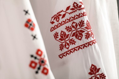 Photo of Beautiful shirts with different embroidery designs, closeup. Ukrainian national clothes