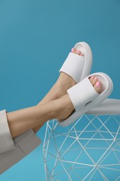 Woman wearing comfortable rubber slippers on light blue background, closeup