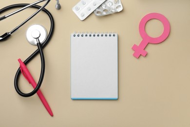 Flat lay composition with female gender sign and stethoscope on beige background. Women's Health concept