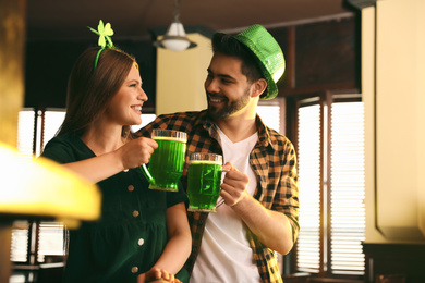 Young man and woman toasting with green beer in pub. St. Patrick's Day celebration