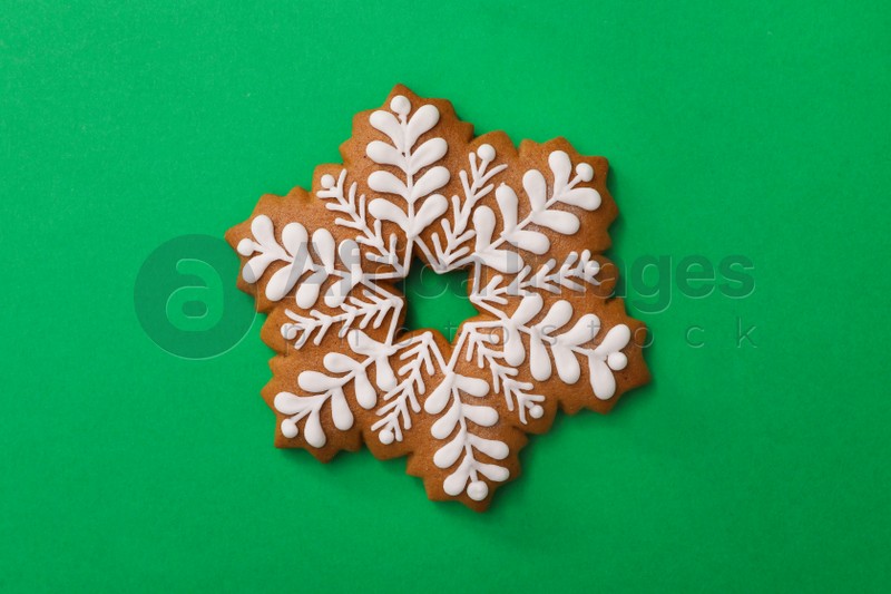 Christmas snowflake shaped gingerbread cookie on green background, top view