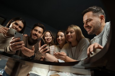 Photo of Friends with drinks and smartphones spending time together in cafe, low angle view