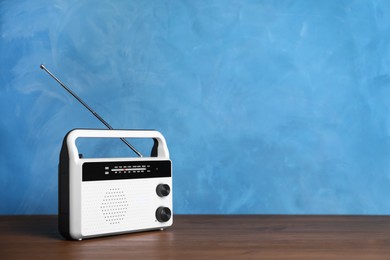 Retro radio receiver on wooden table against light blue background. Space for text