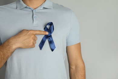 Photo of Man with blue ribbon on grey background, closeup. Urology cancer awareness