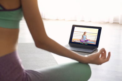 Distance yoga course during coronavirus pandemic. Woman having online practice with instructor via laptop at home, closeup