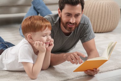 Photo of Father reading book with his child on floor at home