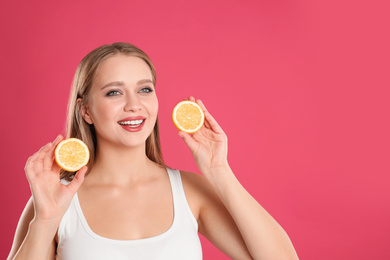 Photo of Young woman with cut lemon on pink background, space for text. Vitamin rich food