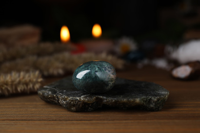 Healing gemstone on wooden table against blurred background