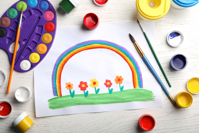 Flat lay composition with child's painting of flowers and rainbow on white wooden table