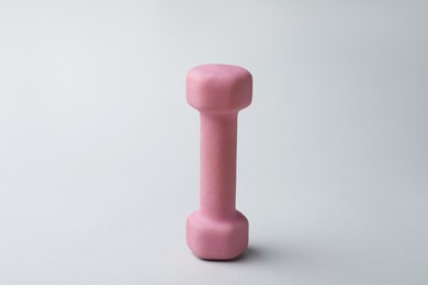 Pink rubber coated dumbbell on light background