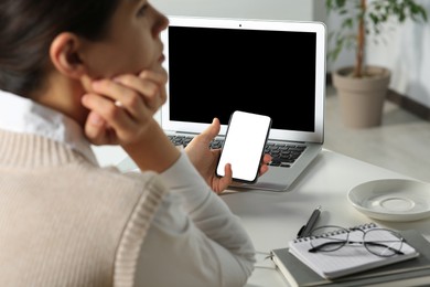 Woman using smartphone at table in office, closeup