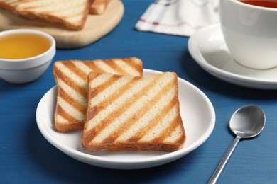 Slices of tasty toasted bread on blue wooden table