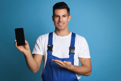 Repairman with modern smartphone on blue background
