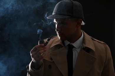 Photo of Old fashioned detective smoking pipe on dark background