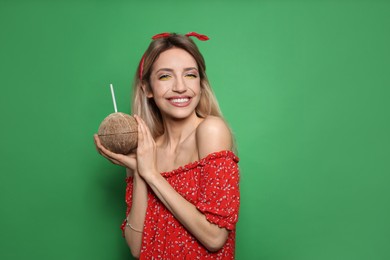 Photo of Young woman with fresh coconut on green background, space for text. Exotic fruit