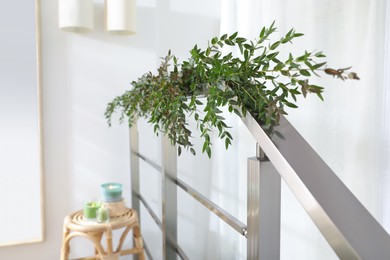 Beautiful garland made of eucalyptus branches on handrail indoors