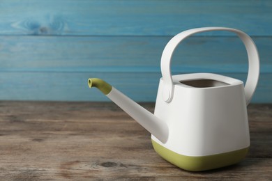 Photo of Modern watering can on wooden table, space for text
