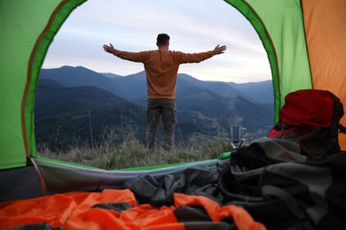 Man enjoying mountain landscape, view from camping tent