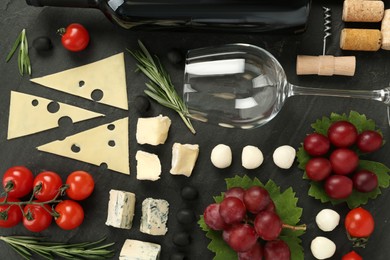 Tasty red wine and snacks on black table, flat lay