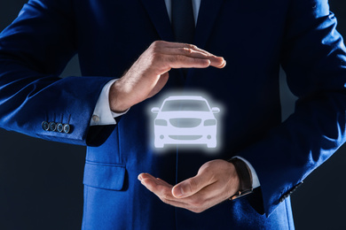 Man demonstrating image of auto on dark background, closeup. Car insurance
