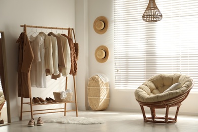 Modern dressing room interior with rack of stylish women's clothes