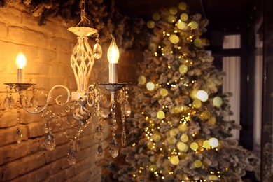 Photo of Beautiful vintage chandelier on ceiling and Christmas tree in room