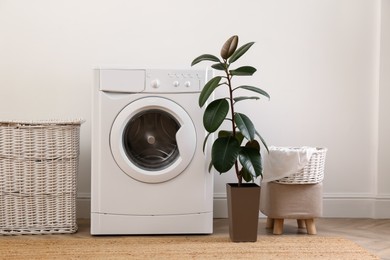 Laundry room interior with modern washing machine and wicker basket near white wall