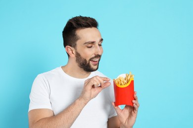 Man with French fries on light blue background