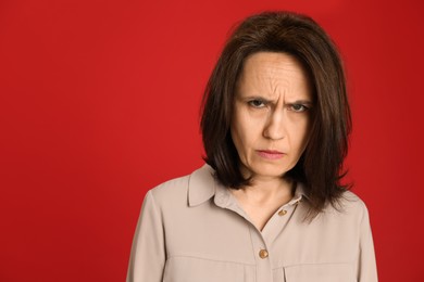 Photo of Portrait of angry woman on red background. Hate concept