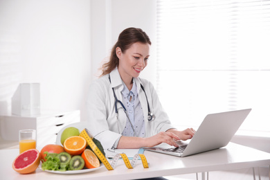 Nutritionist working with laptop at desk in office