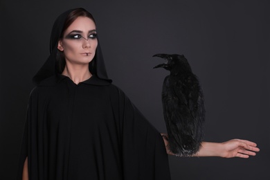 Mysterious witch with raven on black background