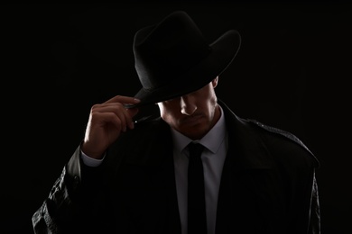 Old fashioned detective in hat on dark background