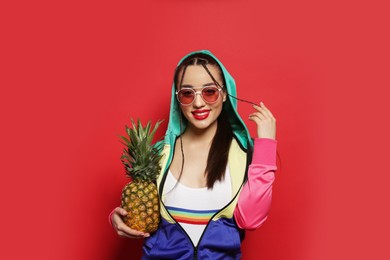 Photo of Young woman with fresh pineapple on red background. Exotic fruit