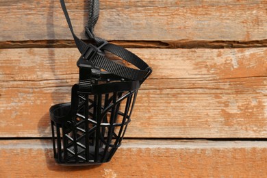 Photo of Black dog muzzle hanging near wooden fence, closeup. Space for text