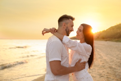 Happy young couple on beach at sunset