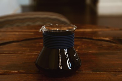 Photo of Cup of aromatic coffee on wooden table in cafe